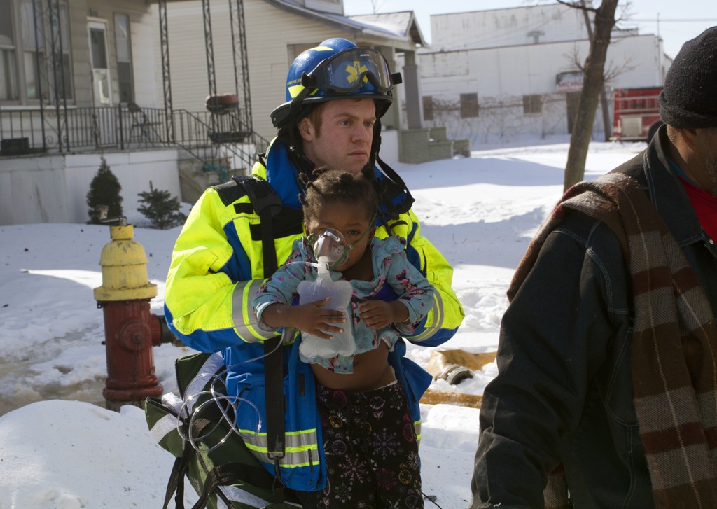 A medic carries a toddler injured in the Marcus St. fire. Photo by Steve Neavling. 