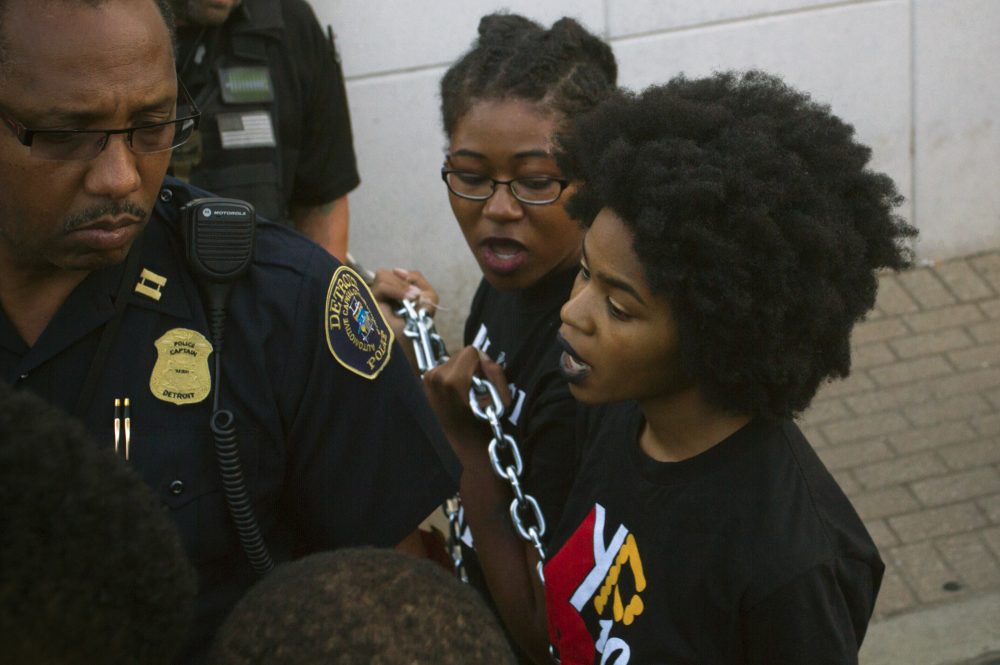 Detroit police arrest protesters who chained themselves to a police precinct. 