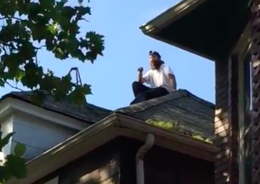 A protester atop a house in Detroit to prevent a demolition. 