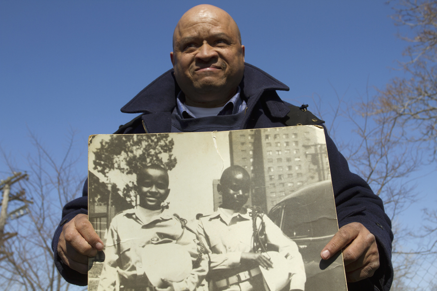 Colbert Prince, who lived at the housing units in the 1950s and '60s, poses with a photo of himself and a friend.