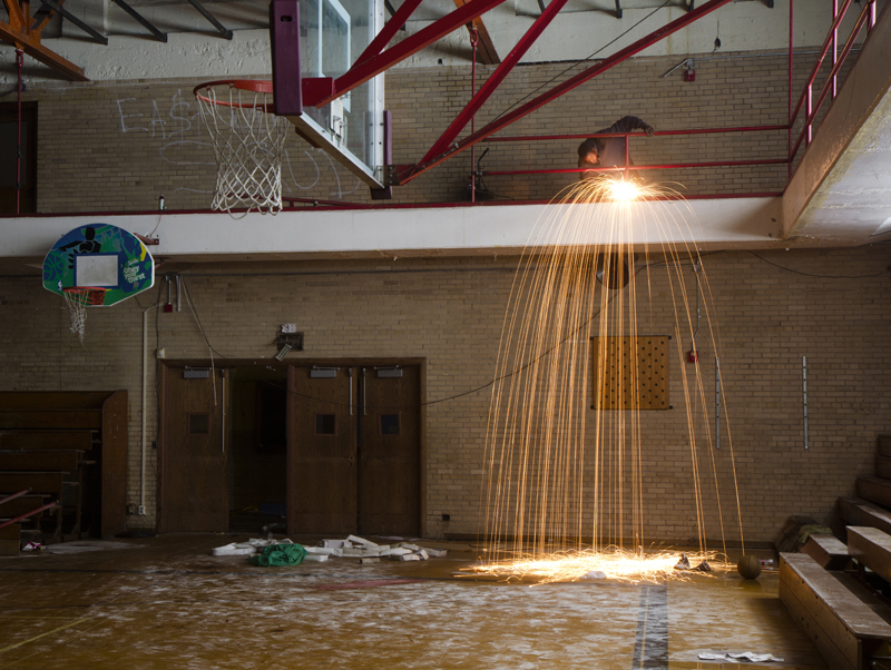 A scrapper removes metal rails from a school gym. 