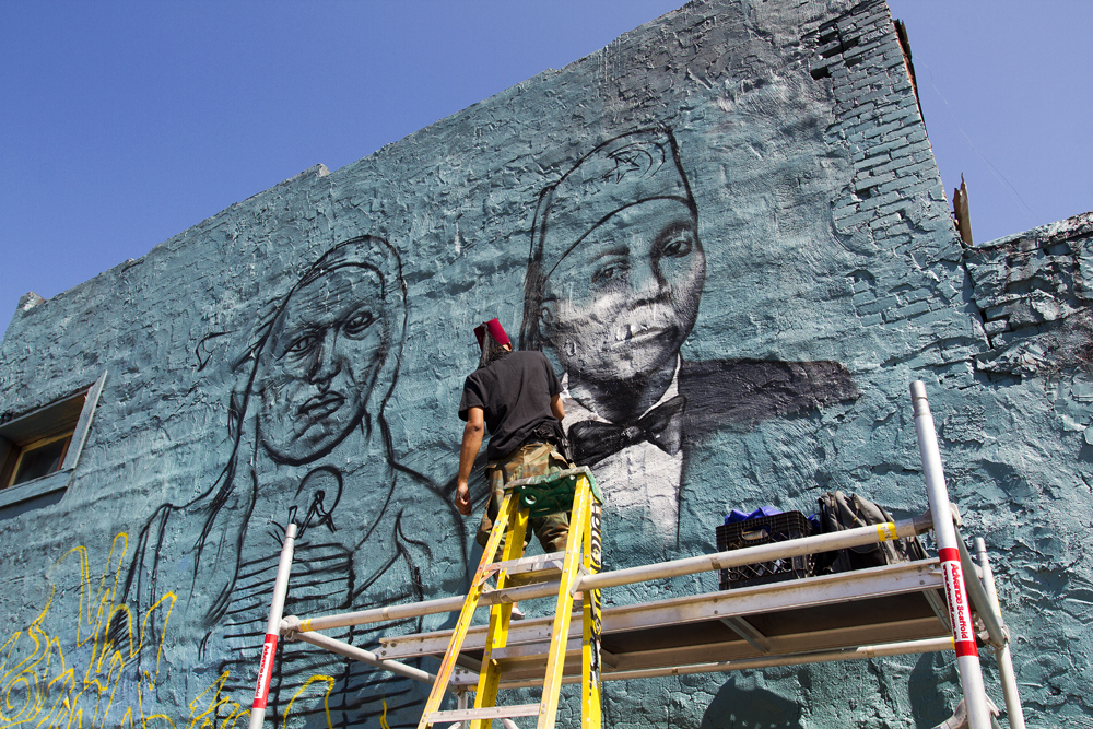 Detroit artist Sintex paints over a tribute to Vincent Chin. 